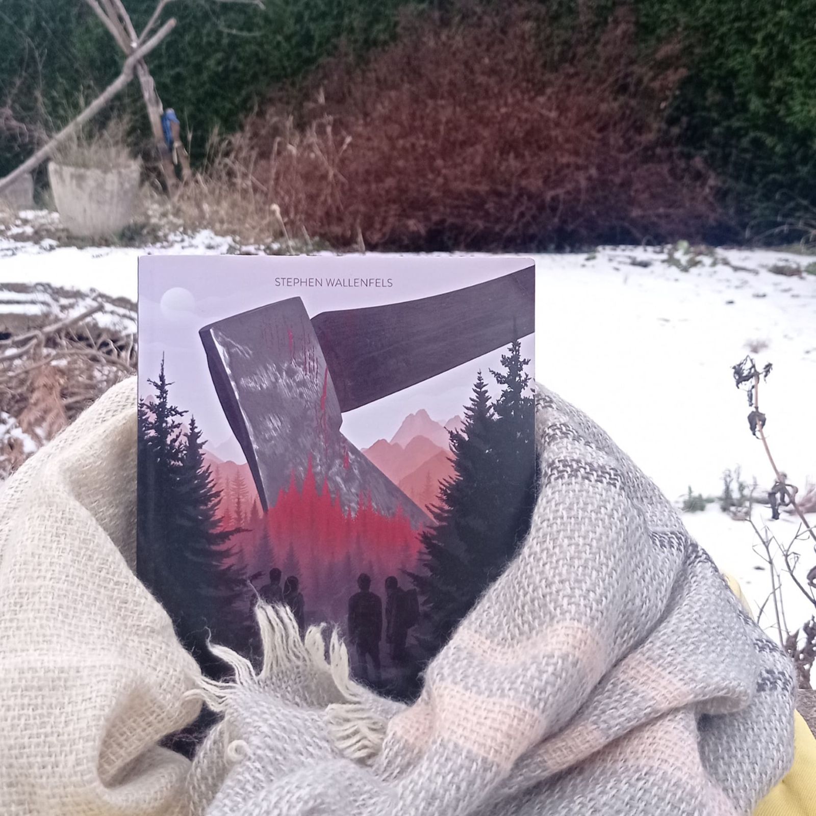 Livre posé dans un jardin enneigé avec une écharpe autour du cou